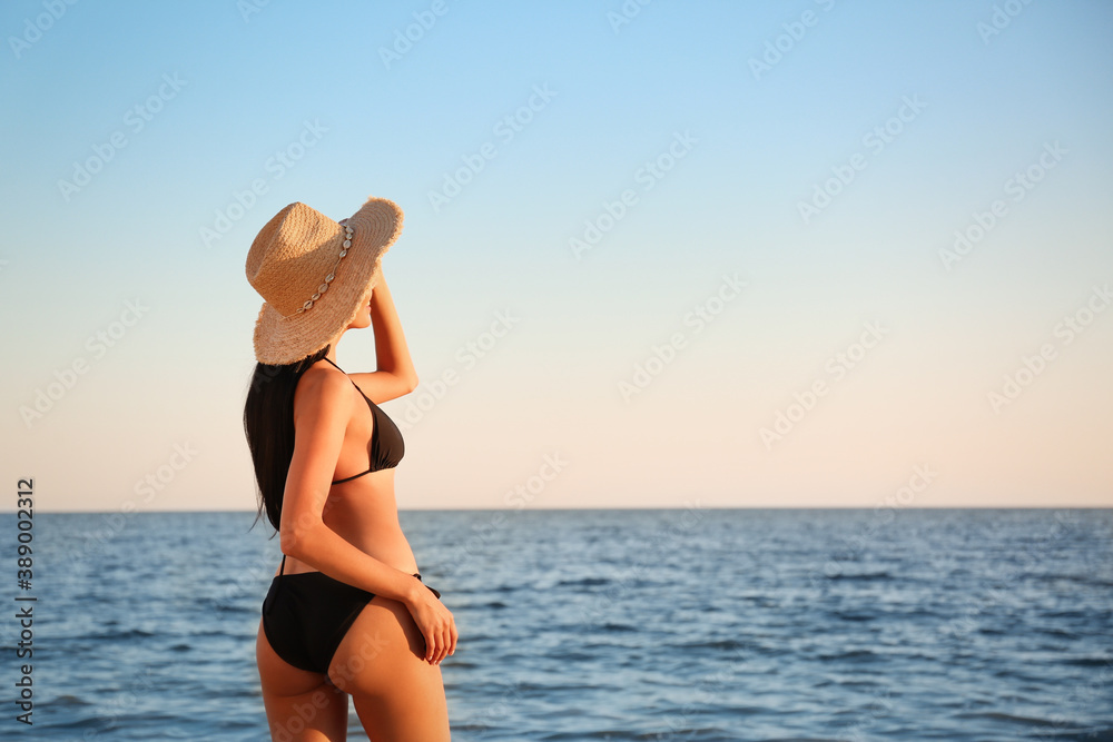 Young woman in black stylish bikini on beach. Space for text Young woman in black stylish bikini on beach. Space for text