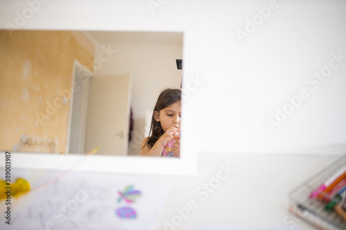 Mirror on a white table reflecting a little girl and a white open door
