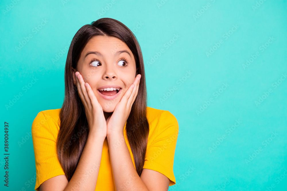 Photo portrait of cute girl touching face with two hands in excitement looking at blank space isolated on bright cyan colored background