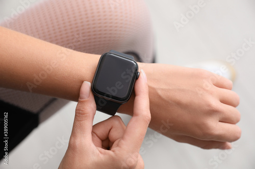 Woman checking stylish smart watch indoors, top view