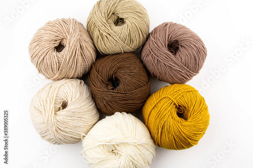 Balls of yarn for knitting brown flowers in a metal basket on a white background.