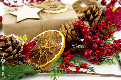 Composition of christmas decor. Craft box, dried orange, red berries.