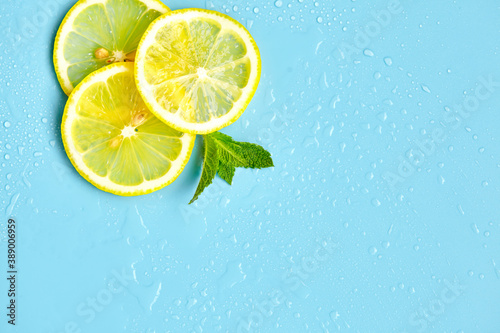 Composition with cut citrus fruits on blue background. Creative summer background composition with lemon slices, leaves mint and ice cubes. Minimal top down lemonade drink concept. Top view