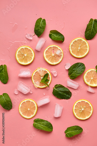 Composition with cut citrus fruits on pink background. Creative summer background composition with lemon slices  leaves mint and ice cubes. Minimal top down lemonade drink concept.Top view