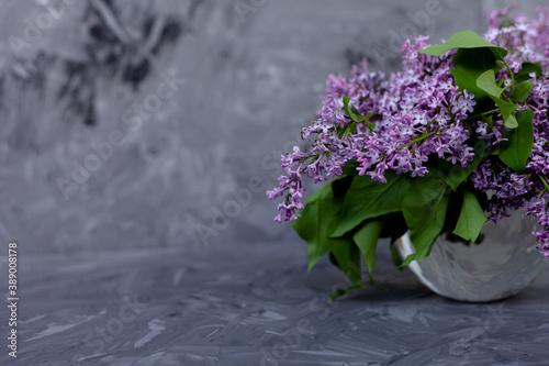 Purple and pink lilac flowers. Bouquet of lilac in glass vase on Against a gray concrete wall. With space for your text - Image