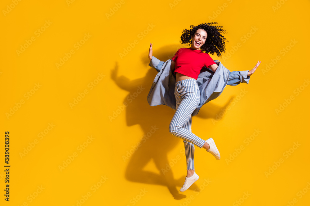 Full length photo of girl jump palms wear striped jeans cropped red t-shirt jacket sneakers isolated yellow color background
