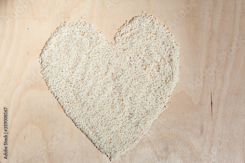 Rice heart on wooden background with place for an inscription. Heart symbol made from rice. Heart made of cereals. Healthy eating