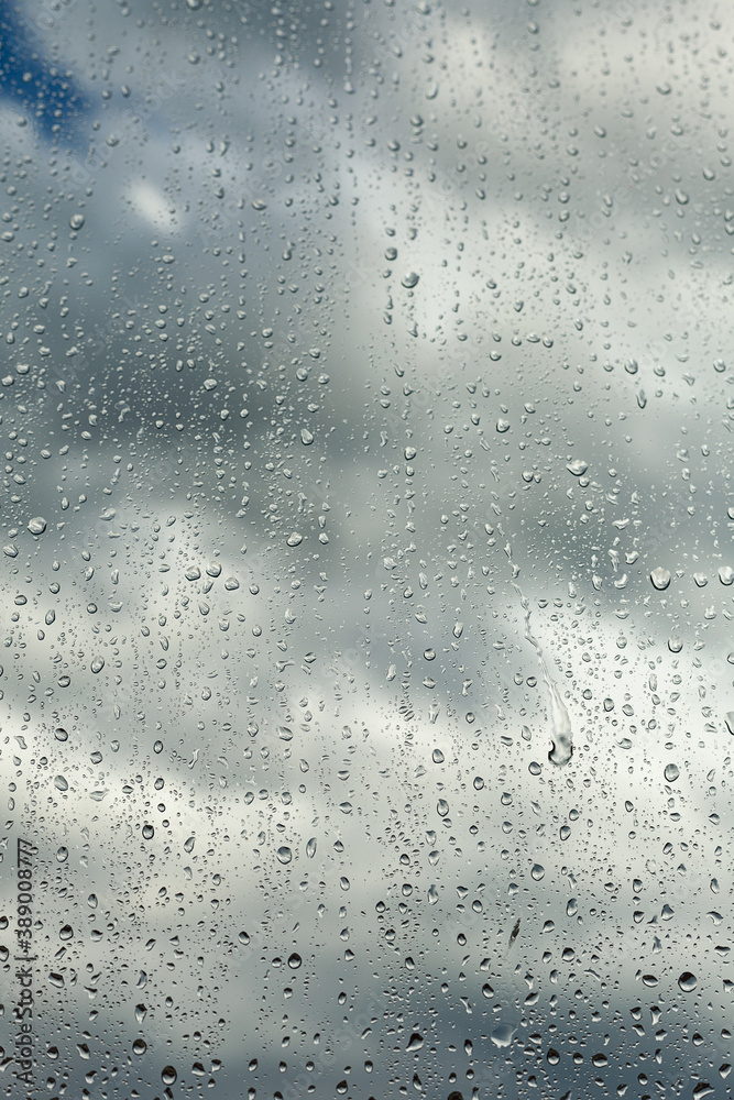 Close up of a window with rain drops falling down. Focus on rain drops. Rain drops on rainy day on outside window glass with blurred edges. Rain outside window pane in spring day. Close up of a window with rain drops falling down. Focus on rain drops. Rain drops on rainy day on outside window glass with blurred edges. Rain outside window pane in spring day.