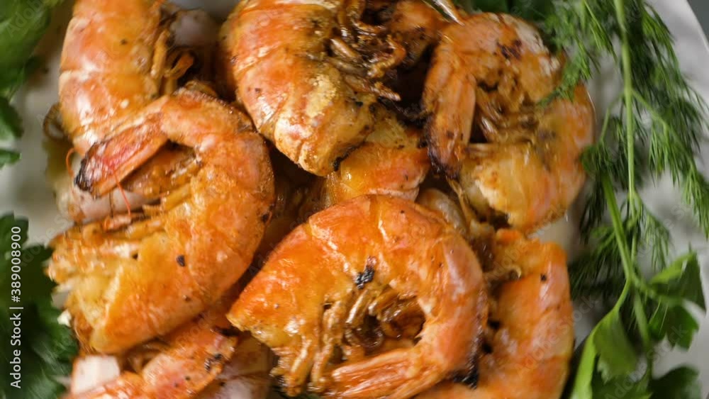 Delicious cooked shrimps with fresh dill and parsley on white porcelain plate turn on table at bright light extreme closeup Delicious cooked shrimps with fresh dill and parsley on white porcelain plate turn on table at bright light extreme closeup