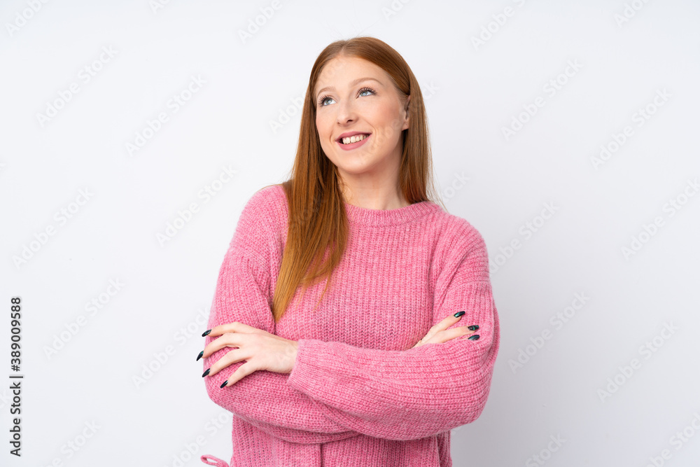 Young redhead woman with pink sweater over isolated white background looking up while smiling