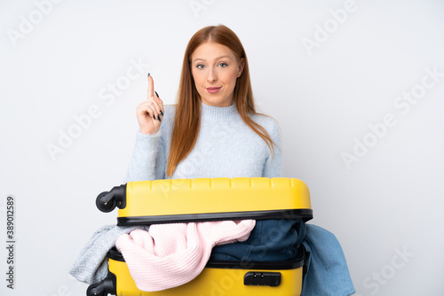 Traveler woman with a suitcase full of clothes pointing with the index finger a great idea