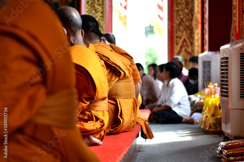 Side or backside of three monk sitting for pray in temple isolated with blurred of group of people.