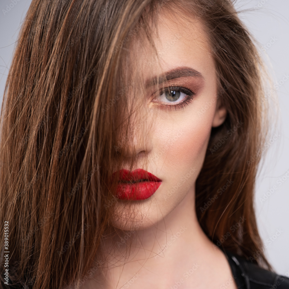 Portrait of beautiful young woman with bright makeup. Beautiful brunette with bright red lipstick on her lips. Pretty girl with long brown hair. Brunette dressed in a black. Sexy girl