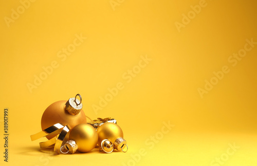 Three golden vintage Christmas baubles on a yellow background with space for your text or image