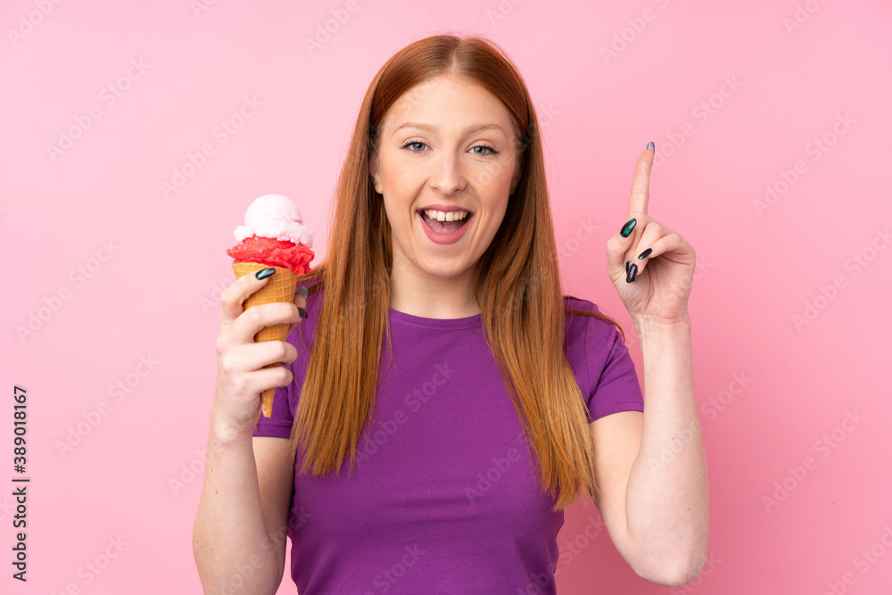 Young redhead woman with a cornet ice cream over isolated pink background pointing up a great idea Young redhead woman with a cornet ice cream over isolated pink background pointing up a great idea