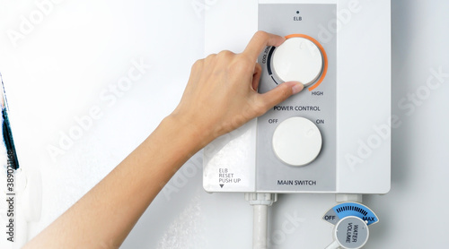  A woman's handsets the temperature of the water in the electric boiler in cold weather.                                  