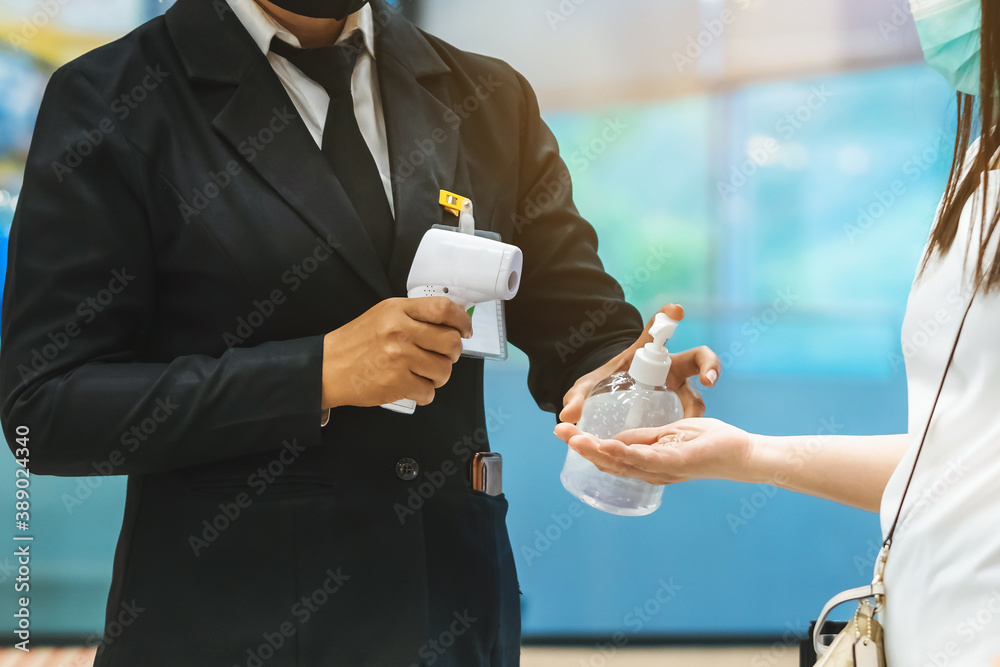 Hand of customer waits for a drop of alcohol gel from female security guard to prevent the spread of germs and bacteria and avoid infections Corona virus (Covid-19) before entering the mall.