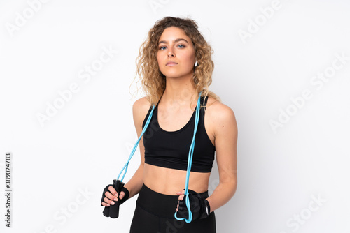 Young sport woman isolated on white background with jumping rope © luismolinero