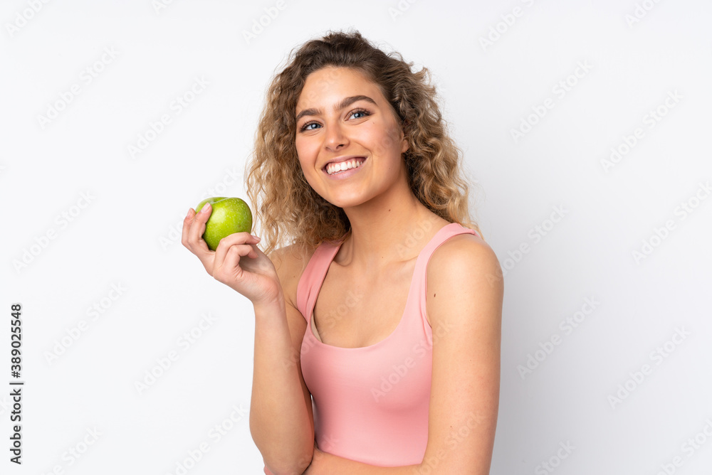 Young blonde woman with curly hair isolated on white background with an apple and happy Young blonde woman with curly hair isolated on white background with an apple and happy