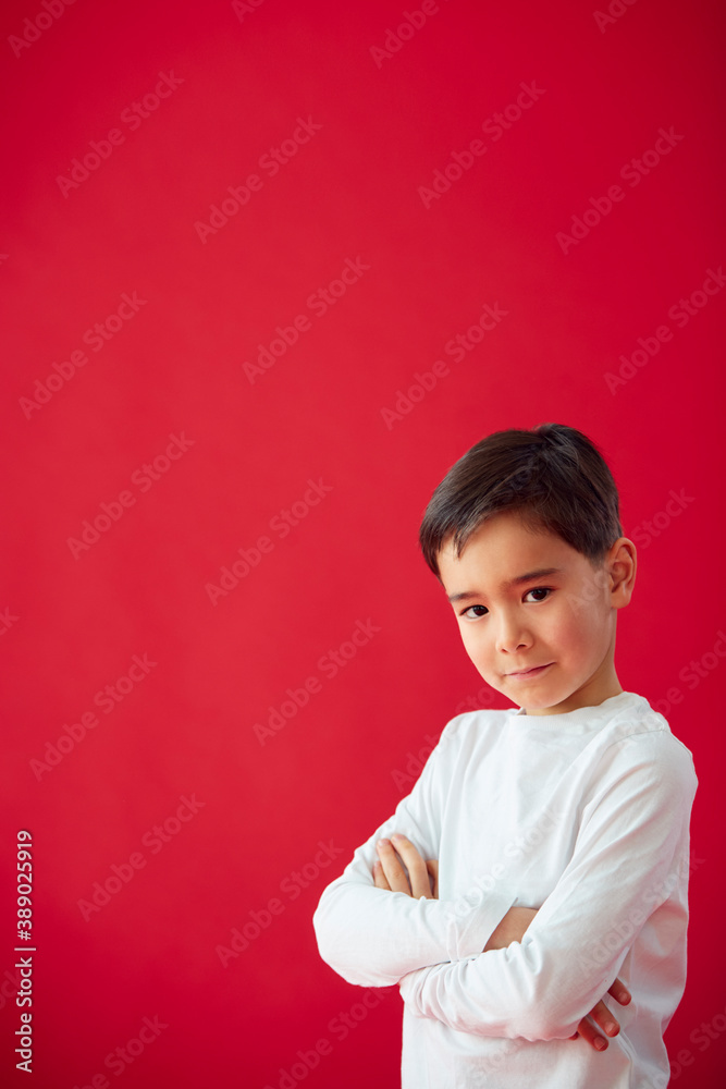 Portrait Of Young Boy With Folded Arms Against Red Studio Background Smiling At Camera Portrait Of Young Boy With Folded Arms Against Red Studio Background Smiling At Camera