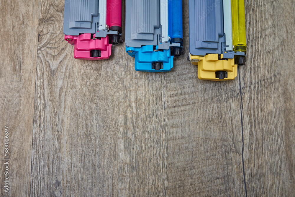 Fototapeta premium Yellow, cyan and magenta toner cartridges on wooden table