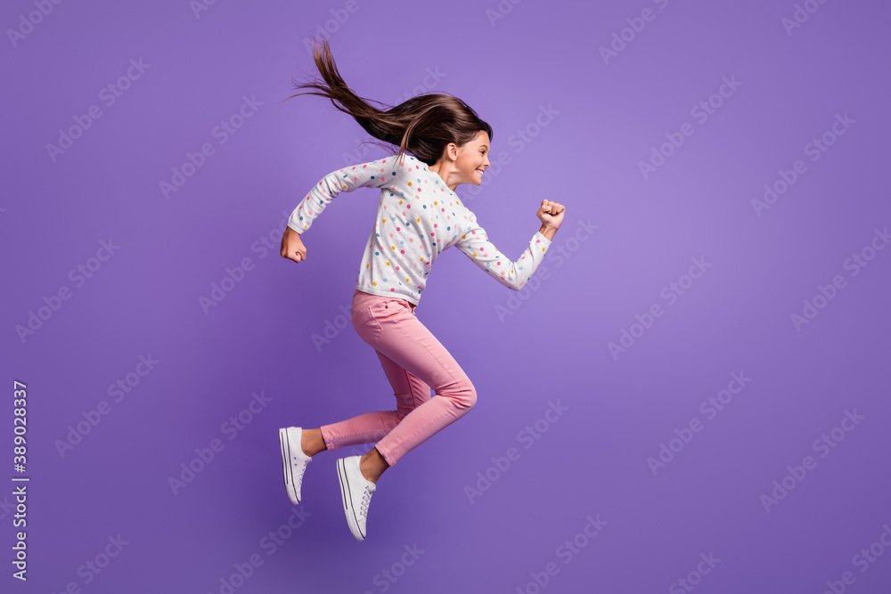 Full length body size side profile photo of jumping high hurrying up preteen girl smiling isolated on vibrant violet color background