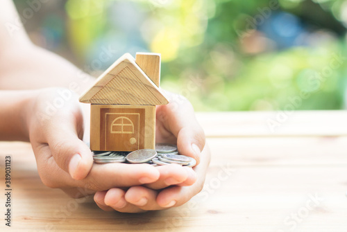 Coins and Home Model are placed on the hands is planning savings money of coins to buy a home concept concept for property ladder, mortgage and real estate investment. for saving or investment
