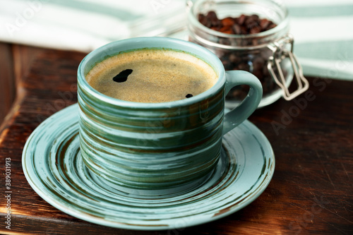 Green cup of coffee on saucer on wooden table