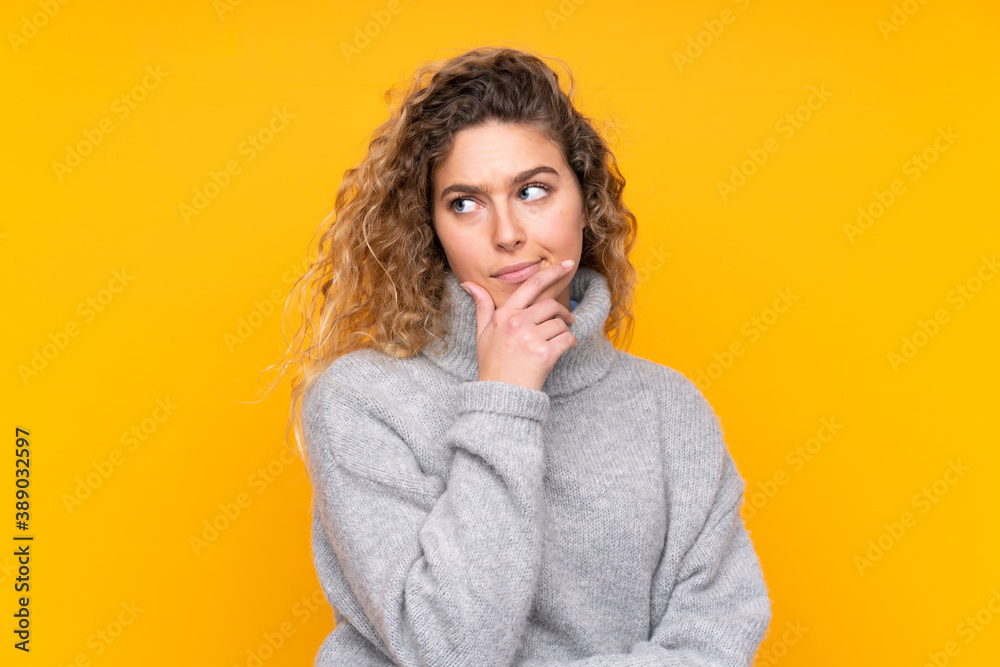 Young blonde woman with curly hair wearing a turtleneck sweater isolated on yellow background thinking Young blonde woman with curly hair wearing a turtleneck sweater isolated on yellow background thinking