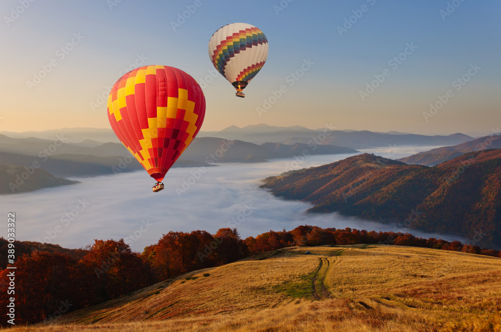 Two hot air balloons fly over the mystical foggy Carpathian mountains