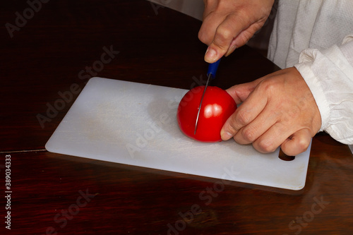 Woman cutting tomato on plastic board, healthy food, vegan food, seitan photo