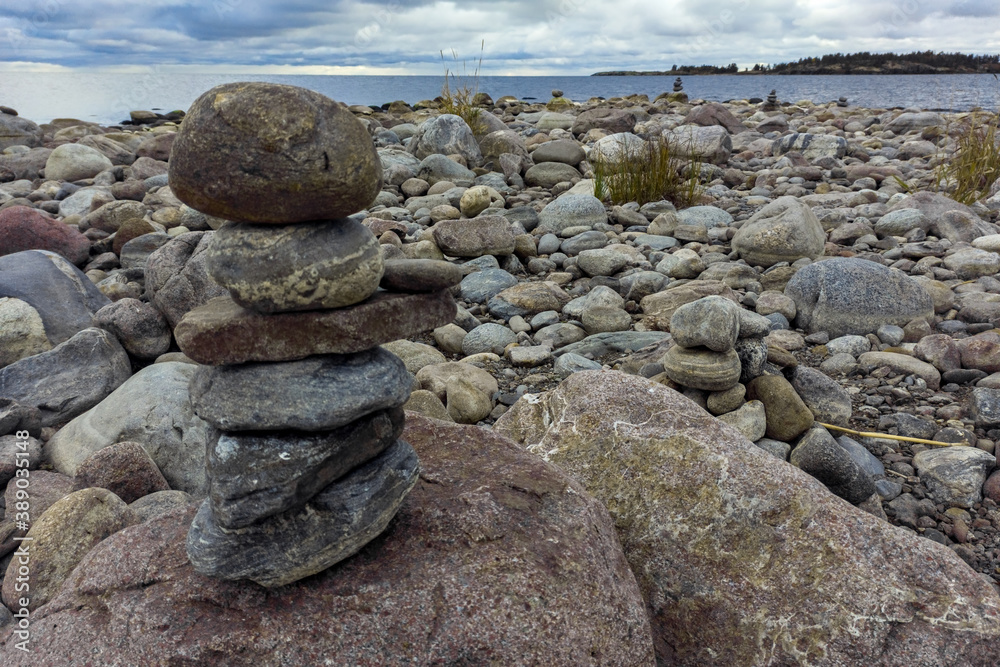 A meditation figure made of stones, folded on a large stone in the middle of a rocky beach overlooking the Ladoga islands on a cloudy day A meditation figure made of stones, folded on a large stone in the middle of a rocky beach overlooking the Ladoga islands on a cloudy day