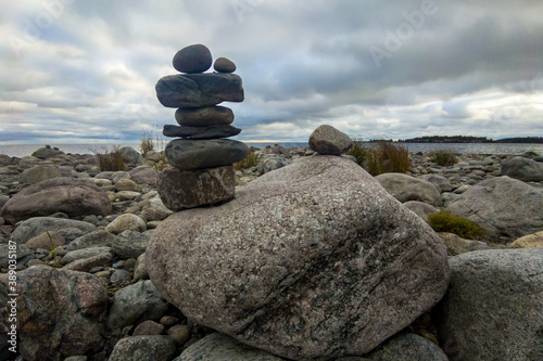 A meditation figure made of stones  folded on a large stone in the middle of a rocky beach overlooking the Ladoga islands on a cloudy day
