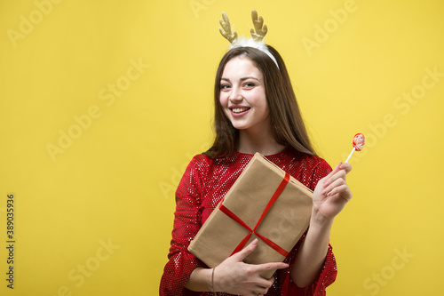 A girl in a red dress with gift against a yellow background.