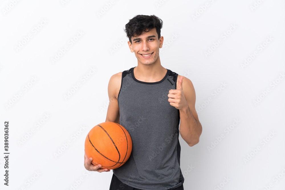 Young Argentinian man over isolated white background playing basketball and with thumb up