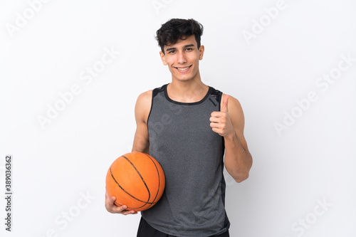 Young Argentinian man over isolated white background playing basketball and with thumb up