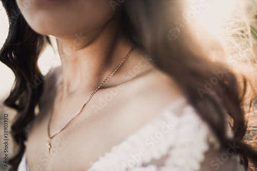 female clavicle tanned girl. Curly-haired bride in a wedding dress in the rays of the sun.