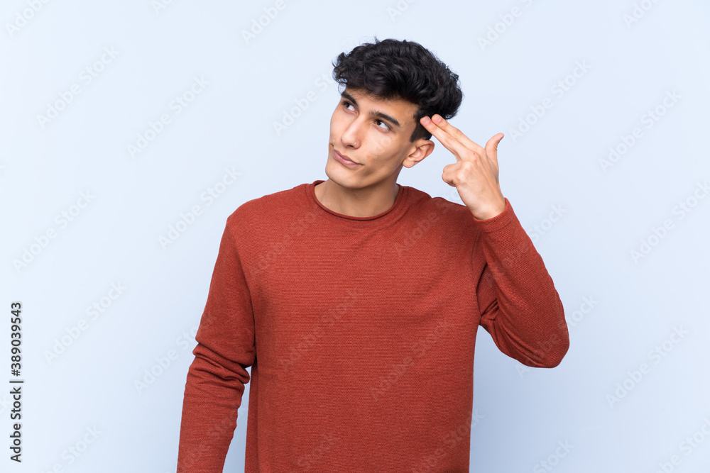 Young Argentinian man over isolated blue background with problems making suicide gesture Young Argentinian man over isolated blue background with problems making suicide gesture