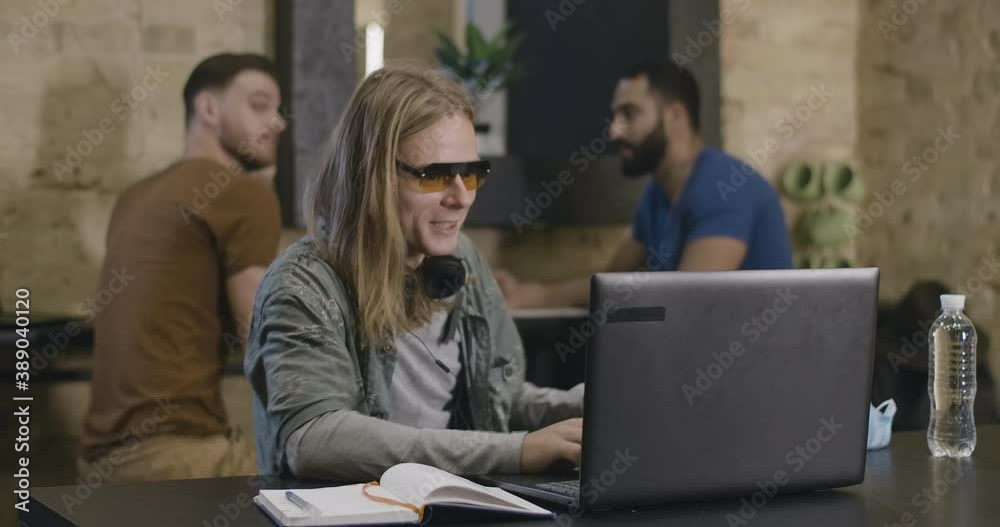 Excited Caucasian man in sunglasses surfing Internet on laptop and calling multiethnic friends to look at screen. Portrait of happy university students resting in hostel. Cinema 4k ProRes HQ. Excited Caucasian man in sunglasses surfing Internet on laptop and calling multiethnic friends to look at screen. Portrait of happy university students resting in hostel. Cinema 4k ProRes HQ.