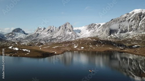 Aerial view of a high mountain landscape with snow and a lake where there are people paddle surfing