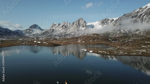 Aerial view of a high mountain landscape with snow and a lake where there are people paddle surfing