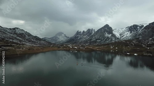 Aerial view of a high mountain landscape with snow and a lake where there are people paddle surfing