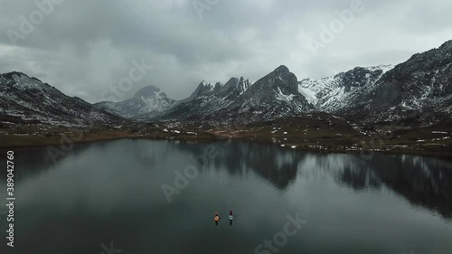 Aerial view of a high mountain landscape with snow and a lake where there are people paddle surfing