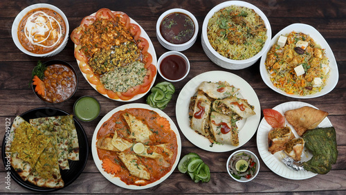 Assorted indian foods chicken biryani,paneer biryani, kulcha, tandoori chicken and spring roll on wooden background. Dishes and appetizers of indian cuisine