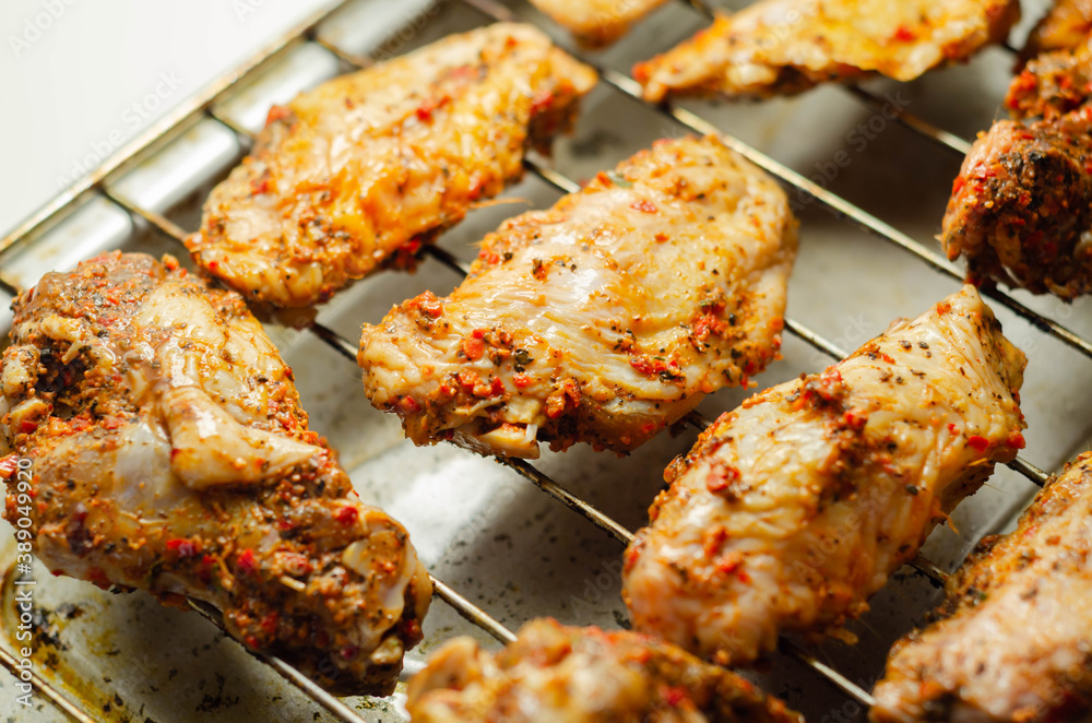 Raw chicken wings with a rendang style rub made with chilli and garlic on the grill tray