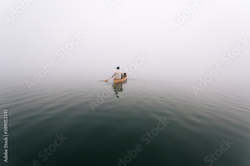 Fotografiet Paddling canoe on the foggy lake