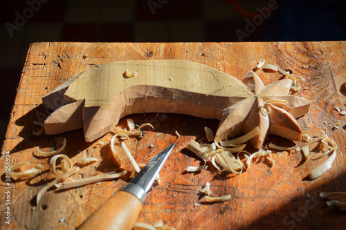 Wood carving from linden wood. Work table in woodworking workshop with carving knife. Woodworking process. 