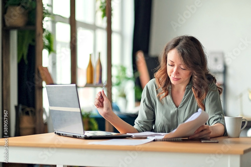 Young woman working from home office. Freelancer using laptop and the Internet. Workplace in living room.
