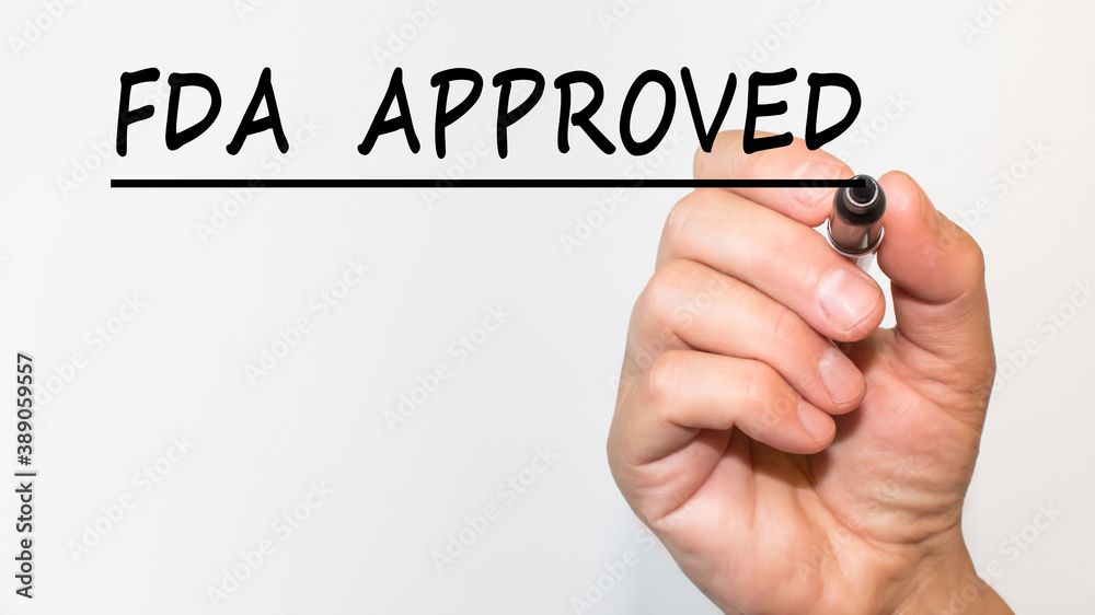 the hand writes text FDA APPROVED with a marker on a white background. business concept the hand writes text FDA APPROVED with a marker on a white background. business concept