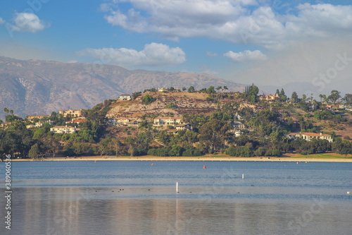 a gorgeous shot of the vast still lake waters with majestic mountain ranges covered with homes and lush green and autumn colored trees at Puddingstone Lake in San Dimas California USA photo